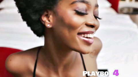 Alicia, curly-haired black MILF smiling seductively in revealing top