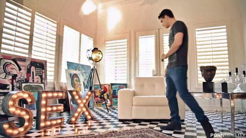 Handsome guy in t-shirt and jeans walks toward giant SEX neon sign in stylish art-filled room