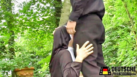 Ashley Dark in hijab kneeling for blowjob, gripping man's crotch outdoors