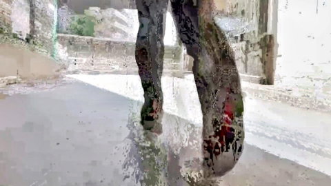 Skinny girl's wet torn pants legs splashing in street puddle