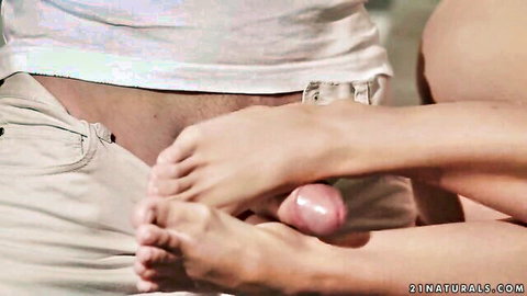 Skinny fair-skinned young woman gives footjob to erect pink cock with her soft soles