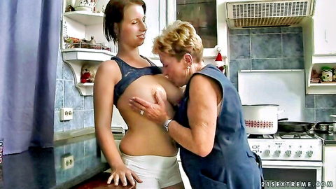 Mature granny sucking young woman's exposed breasts in lesbian encounter