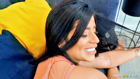 Busty brunette smiling seductively on couch in sheer top teasing big tits