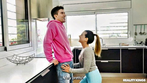 Pretty brunette in ponytail kneels gripping guy's thighs teasing blowjob in kitchen