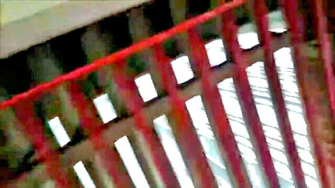 Close-up of red metal railings in outdoor parking structure with blurred bars