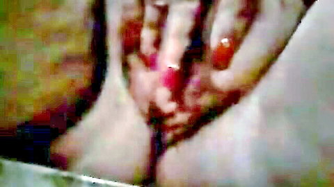 Close-up of mature woman rubbing her pink pussy with red nails