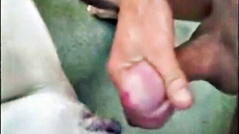 Woman's hand gripping ebony cock with fresh cum, intense close-up