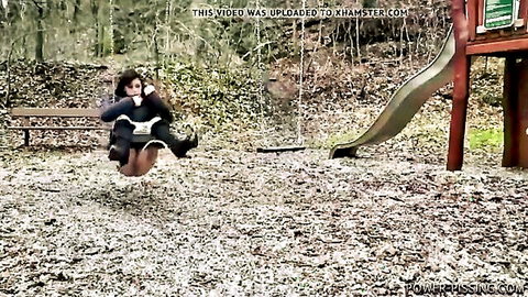 Brunette woman squatting on playground swing in black dress, pissing outdoors