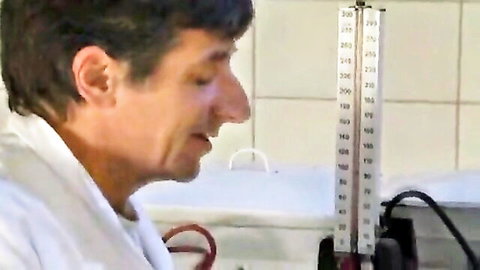 Brunette doctor checking blood pressure on arm in tiled medical clinic