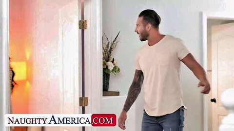 Tattooed handsome man smiling in bedroom doorway ready for naughty action
