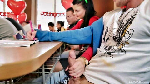 Brunette schoolgirl handjobs exposed hard cock under classroom desk with onlookers