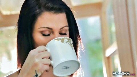 Seductive brunette babe sipping coffee with teasing gaze and cleavage
