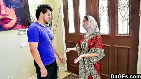 Young guy in blue shirt chats with hijabi Arab MILF in red dress at door