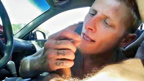 Tattooed guy gives gay blowjob to driver steering car with one hand on wheel