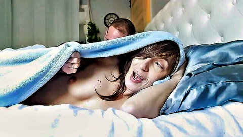 Moaning brunette babe with bare tits exposed as redhead hunk hides under blanket eating her pussy