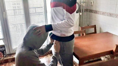Hooded guy pulls down grey sweatpants exposing bare ass in kitchen while buddy gropes cheeks behind