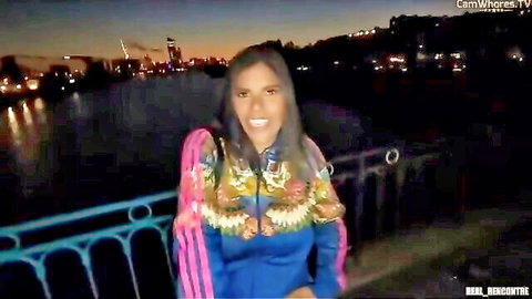 Smiling Venezuelan woman in colorful open jacket showing cleavage outdoors at dusk