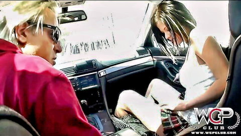Blonde girl in plaid skirt spreads legs flashing white panties in car while driver watches