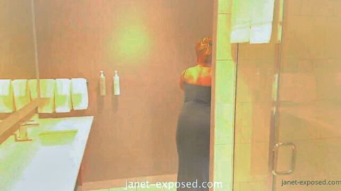 Janet Mason in tight gray dress, teasing from behind in bathroom