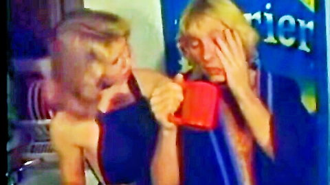 Blonde with grapefruit tits in blue top holding mug, classic porn scene
