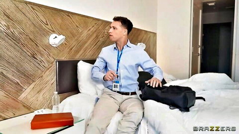 Handsome businessman in blue shirt sitting on hotel bed with backpack and badge.