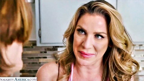 Tanned blonde MILF with big fake tits in pink top confronts brunette woman in kitchen