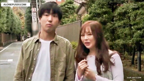Young Japanese couple standing closely on tree-lined urban street in casual clothes
