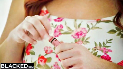 Redhead babe in floral dress grips pink toy teasingly with both hands