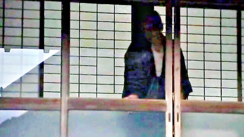 Pretty Japanese housewife in dark top, gazing seductively through wooden screens
