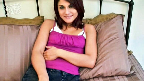 Smiling Middle Eastern teen in pink tank top and jeans on bed