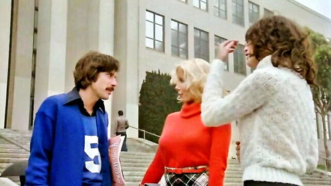 Vintage 1978 erotic scene: blonde in red turtleneck and plaid skirt with brunette and shaggy-haired guy outside school