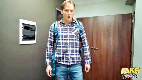 Surprised amateur guy in plaid shirt and backpack at fake hotel entry