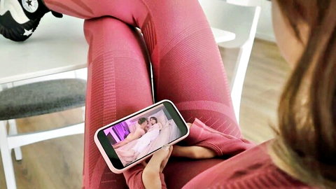 Fit woman in pink leggings watches explicit anal sex video on phone