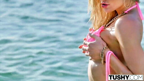 Blonde bombshell Kenzie Anne in pink bikini teasing on beach