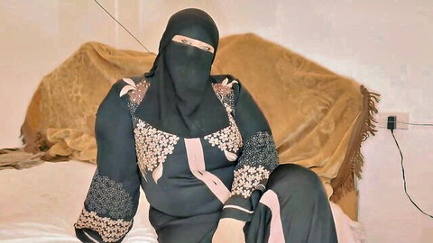 Niqab Muslim woman in tight embroidered abaya teasing on bed spreading thighs seductively