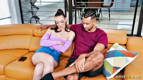 Tattooed brunette babe in purple top and tiny jean shorts cuddles muscular dreadlocked black stud on couch