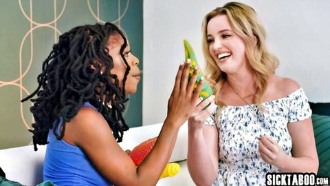 Ebony and blonde girlfriends smiling playfully holding big green dildo toy