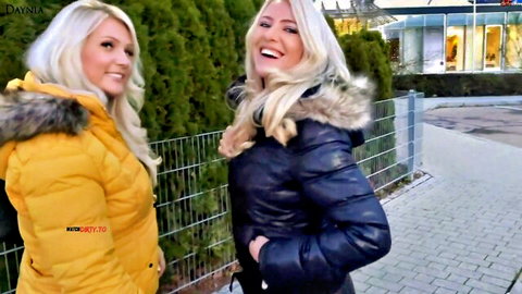 Two smiling blonde women in fur-trimmed jackets at outdoor parking lot, Daynia FFM scene