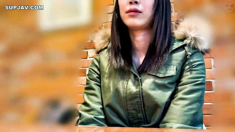 Sexy Asian teen in shiny green leather jacket with fur hood pouting seductively.