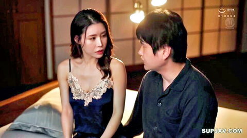 Japanese MILF in lace camisole showing big tits cleavage stares intensely at man on bed
