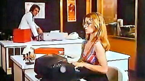 Blonde secretary in revealing halter top typing at desk with suited man nearby