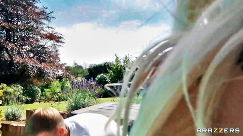 Blonde woman with flowing hair teasing outdoors in garden with man in white shirt Brazzers