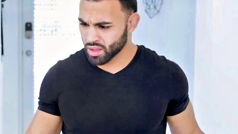 Muscular bearded Arab man in tight black V-neck shirt with intense angry expression