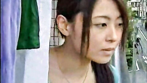 Japanese woman peeking through hanging purple and green clothes with seductive gaze