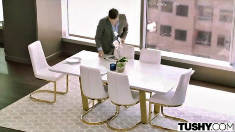 Suited businessman leaning over white conference table in luxury office with city view Tushy scene