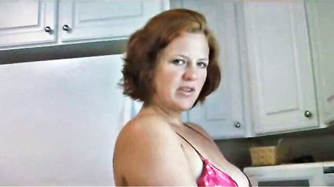 Curvy redhead in pink lingerie exposing big tits in kitchen tease