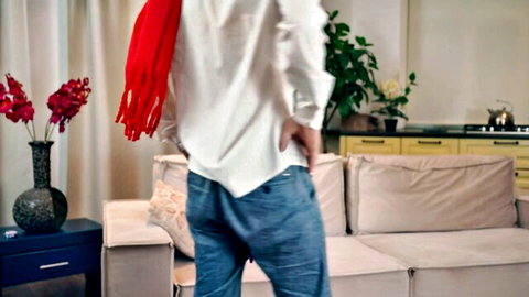 Man standing with hands in pockets exposing butt crack in low jeans in living room