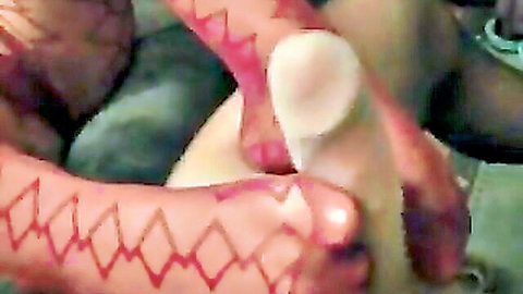 Woman in red patterned pantyhose giving footjob closeup