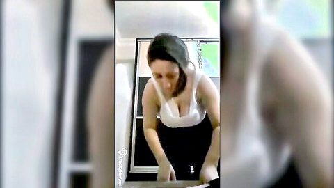 Busty mature MILF bends over mirror in tight white tank top showing massive cleavage and thick ass