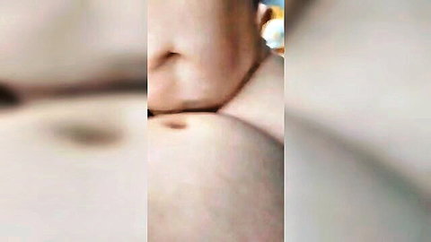 Close-up of woman's bare nipple and areola with yellowish drop, blurred breastfeeding view